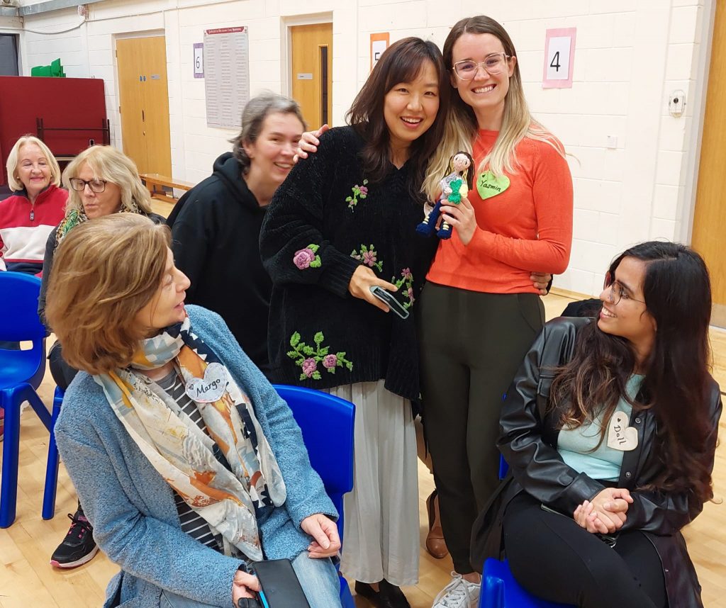 Members of Fermoy International Choir smile at a hand knit doll, which choir member Jina made as a gift for choir member Yasmin.